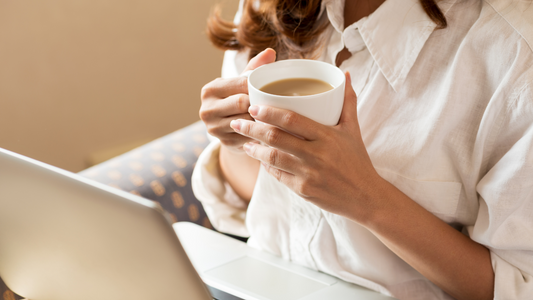Faceless woman holding a coffee cup while working on a laptop, representing relaxed and flexible content creation for solopreneurs.